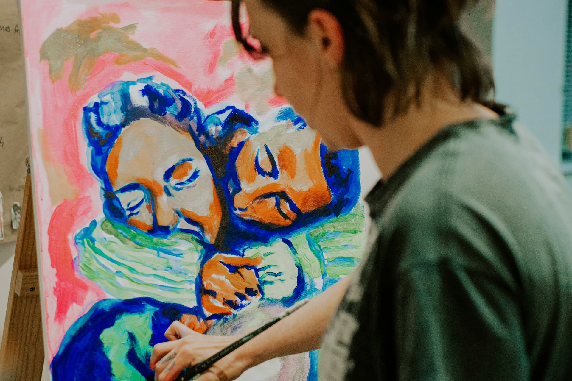 An artist painting two embracing figures in bright colours