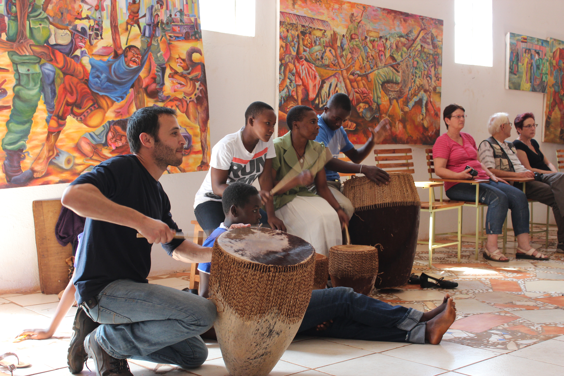 A drumming circle in a gallery of community paintings