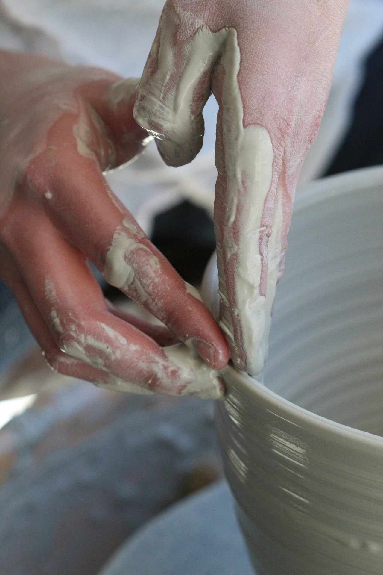Hands shaping a vessel on a potter's wheel