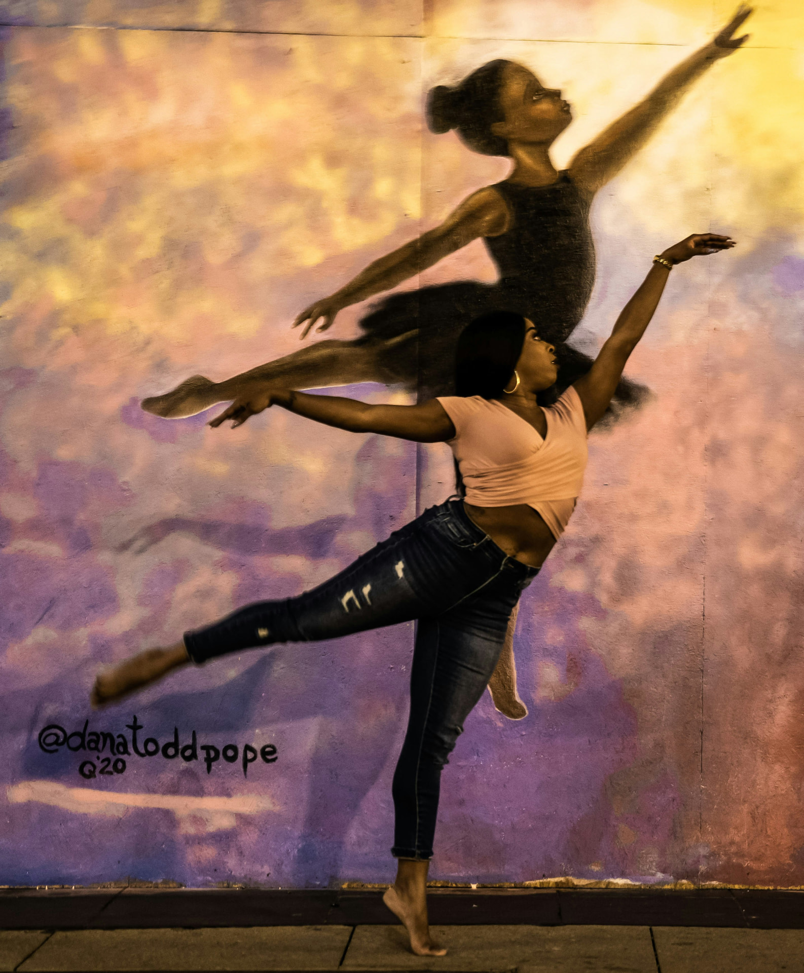 A dancer leaping in front of a mural of her own mirrored figure