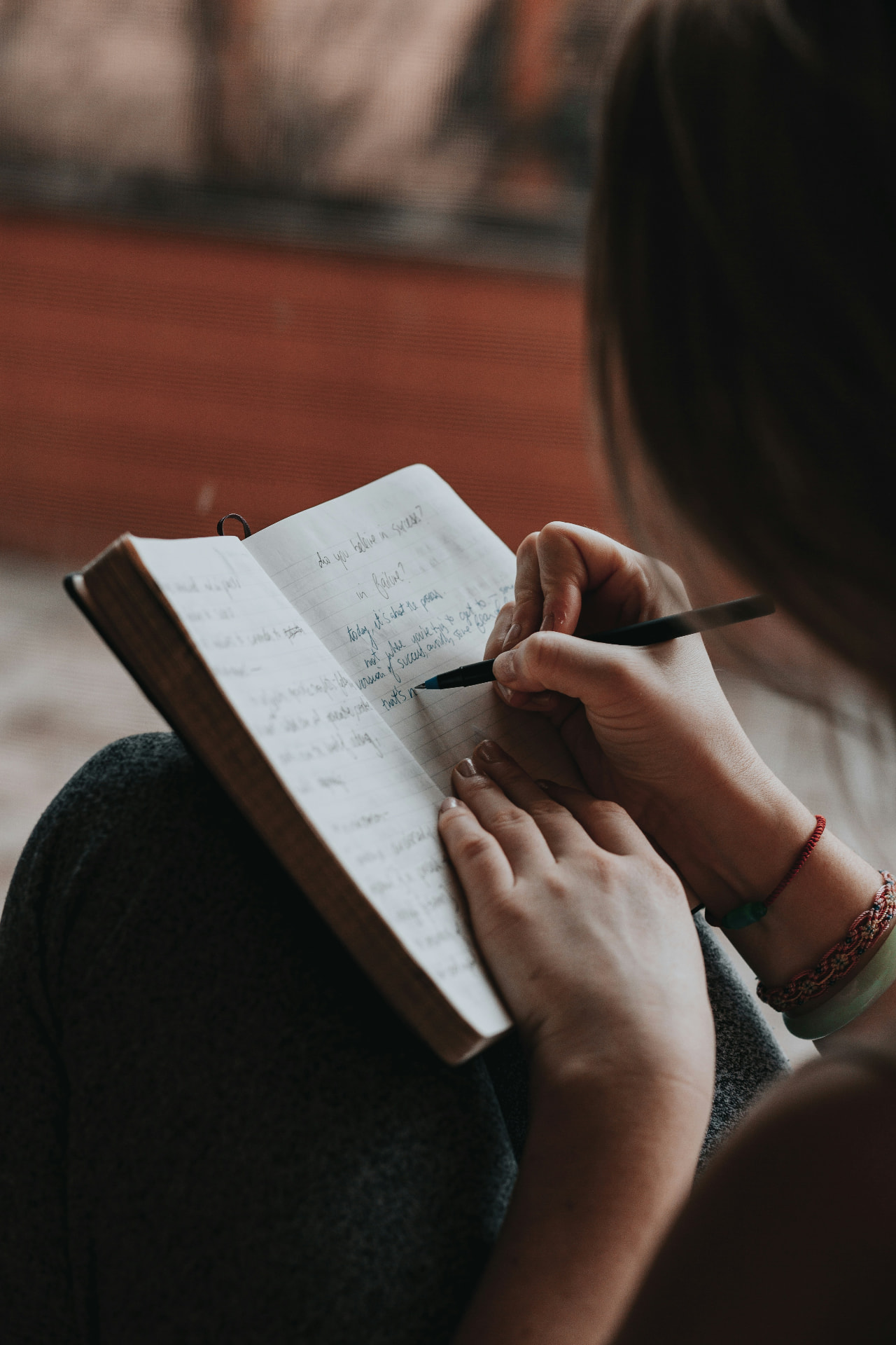 A person writing reflections by hand in a notebook